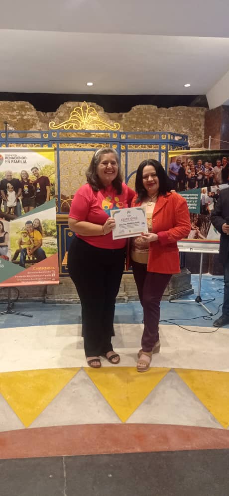 man wearing a black jacket, white shirt, blue jeans, and brown boots, playing a white electric guitar while sitting on an amp